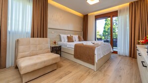 Quarto moderno com cama grande, sofá, mesa de cabeceira e vista para o exterior.