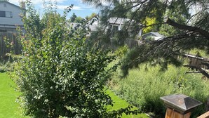 A wooden deck with a metal railing, surrounded by a well-maintained lawn and dense shrubbery. - MileHi Vacation Home (near DIA, pet friendly, has a baby crib) (Aurora)
