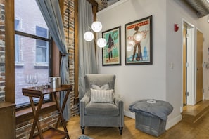 Relax in a cozy room with a comfortable armchair, wooden floor, and a bench for extra seating.