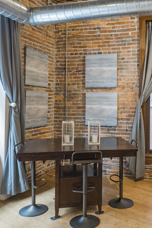 Relax in this cozy corner room with a brick wall, exposed ductwork, and a window offering a view of the outside.