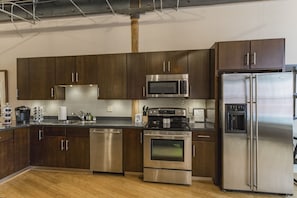 Enjoy cooking in this well-equipped kitchen with a microwave, oven, and refrigerator, along with a spacious dark cabinet area and tiled backsplash.