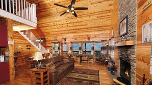 A cabin interior with a wooden interior, a fireplace, a sofa, and a dining area. - Steamy Soaks with Scenic Views, Fireside Chats, Outdoor Showers & Game Nights - Jackson's Cabin (Sevierville)