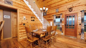 A wooden cabin interior with a dining area, a staircase, and a view of the mountains. - Steamy Soaks with Scenic Views, Fireside Chats, Outdoor Showers & Game Nights - Jackson's Cabin (Sevierville)