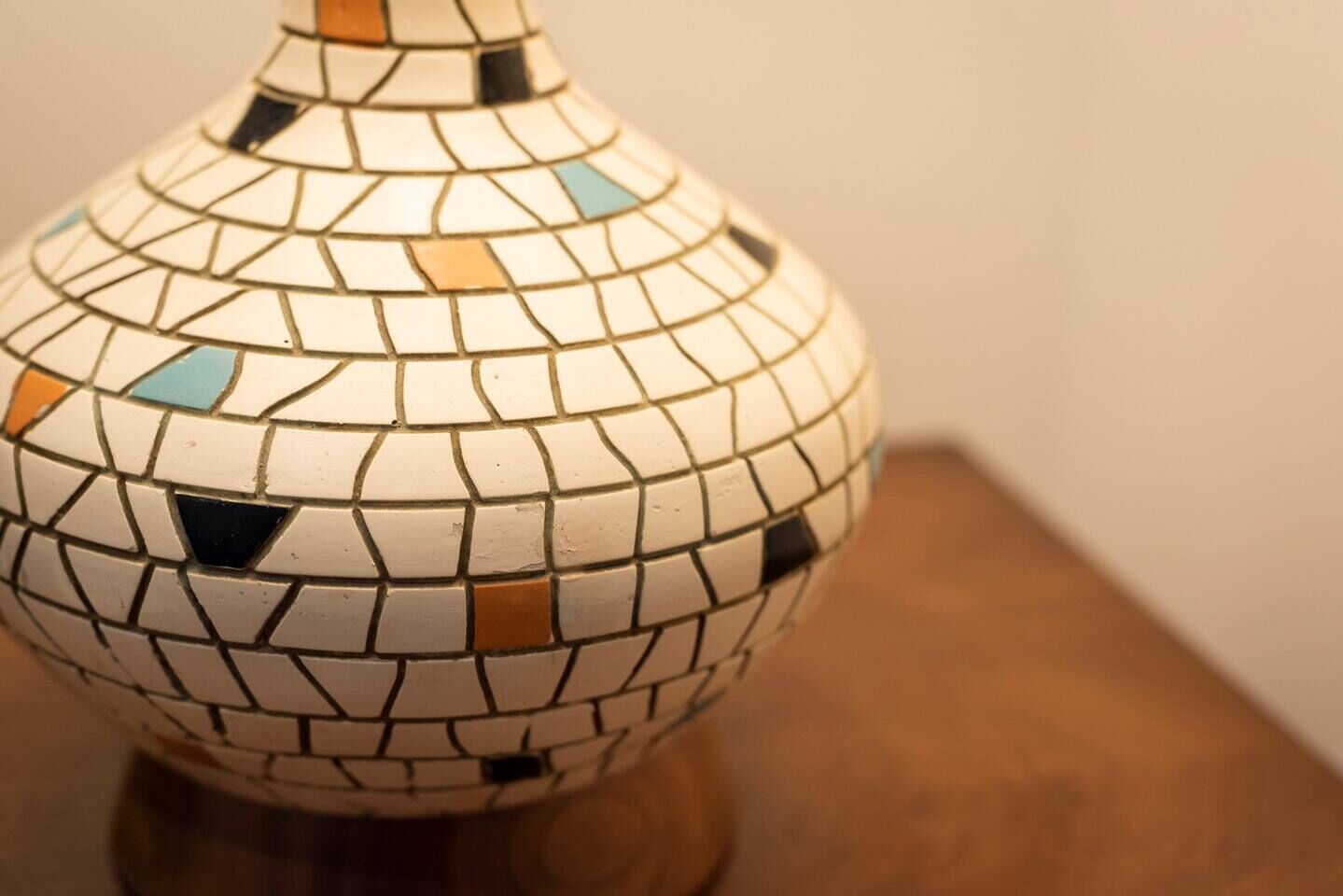Eine Vase mit Mosaikmuster auf einer Holztischplatte.