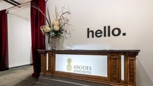 A reception desk with a sign reading "ABODES APARTHOTEL" and a decorative vase with flowers. - Fresh, Sleek, and Contemporary Executive Apartment (Rochester)
