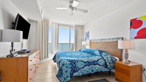 A hotel room with a bed, a desk, a chair, a TV, and a balcony with a view. - So many amenities! Oceanfront condo w/outdoor features, pools, lazy river, kids' pool (North Myrtle Beach)