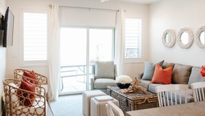 A spacious living room with a large sliding glass door leading to a balcony, a ceiling fan, and a seating area with a sofa and chairs. - North Hampton | Pool, Hot Tub & Family-Friendly Spaces Near St. George (Washington)