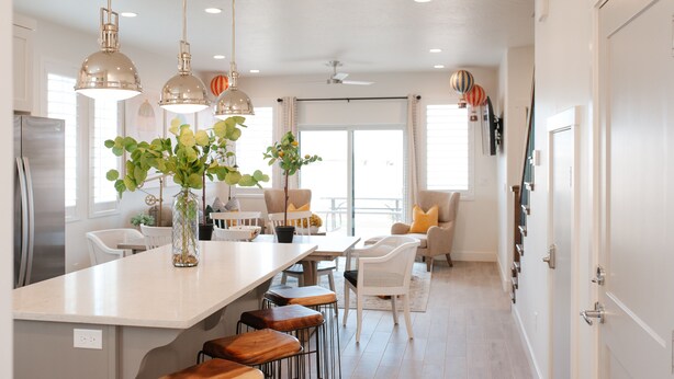 A modern kitchen with a central island, pendant lighting, and a dining area with white chairs and a sofa. - Up Up and Away – Colorful Southern Utah Escape Near Zion & St. George (Washington)