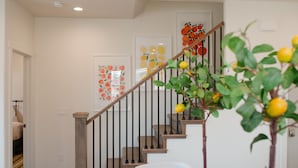 A staircase with a wooden handrail and black balusters, leading to a landing with a white chair and a small table. - Up Up and Away – Colorful Southern Utah Escape Near Zion & St. George (Washington)