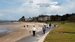 Una playa con gente caminando y un sendero a lo largo de la orilla.