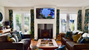 Sala de estar con dos sofás, una mesa de centro y una chimenea. Un televisor de pantalla plana está montado sobre la chimenea.