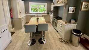 Una cocina moderna con una isla central, muebles blancos, una estufa y una ventana con vistas a zonas verdes.