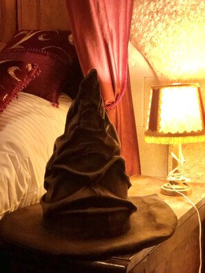 A bed with a dark blanket, a bedside lamp, and a curtain.