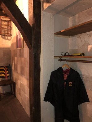 A room with a wooden bench, a hanging robe, and a shelf with glasses and a yellow item.