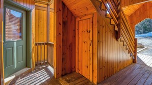 Un intérieur en bois avec une porte verte, un escalier et une terrasse en bois à l’extérieur.