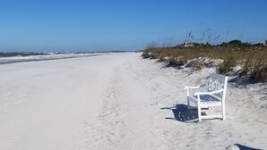 En vit bänk på en sandstrand med en klarblå himmel.