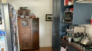 Une cuisine avec des meubles de rangement en bois, un réfrigérateur, une cuisinière et des luminaires suspendus.