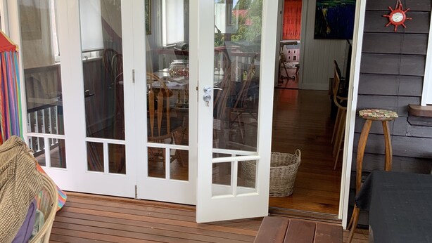 Une terrasse en bois avec une porte-fenêtre coulissante donnant sur un espace intérieur.