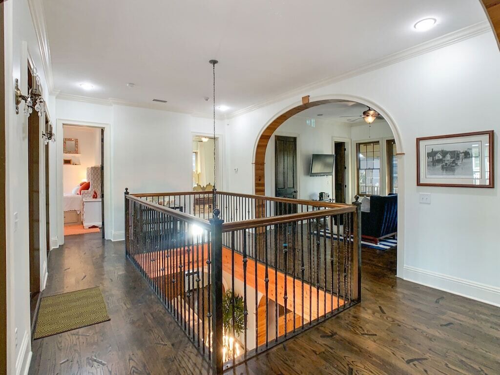 Ein geräumiger Wohnbereich mit Holzboden, einem Balkon mit Metallgeländer und einer Treppe zu einer oberen Ebene.