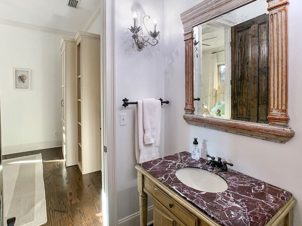 A bathroom with a marble sink, wooden vanity, and a large mirror with a wooden frame.