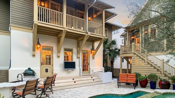 Une maison à deux étages dotée d’un balcon, d’un espace salon extérieur et d’une piscine.