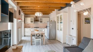 A modern kitchen with wooden beams, white cabinets, and a dining area with a table and chairs. - GuestHost - Apartment of about 80 sqm, perfect for 4/6 people (but it can host up to 7 people), located in a pedestrian area, on the ground floor of a renovated house overlooking Lake Como. The property is located in the historic centre of the enchanting (Carate Urio)