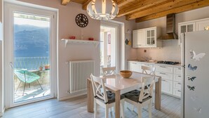 A kitchen with white cabinets, a wooden ceiling, and a view of the mountains through a glass door. - GuestHost - Apartment of about 80 sqm, perfect for 4/6 people (but it can host up to 7 people), located in a pedestrian area, on the ground floor of a renovated house overlooking Lake Como. The property is located in the historic centre of the enchanting (Carate Urio)