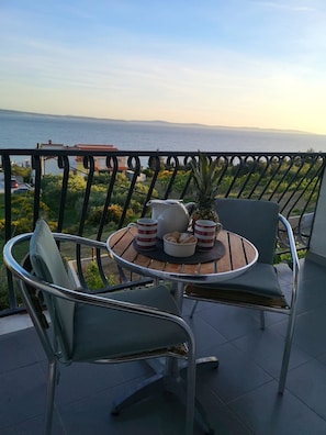 Enjoy a romantic breakfast for two on this balcony overlooking the sea and distant hills.