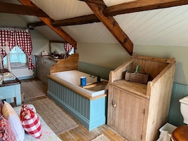 A rustic kitchen with a wooden bench, a sink, and a window with checkered curtains.