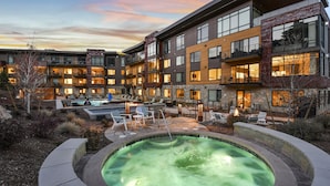 A modern hotel with a heated outdoor pool, lounge chairs, and a well-lit courtyard.
