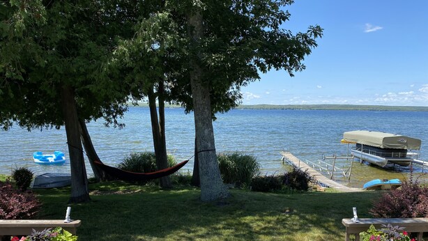 A wooden deck with a hammock, a floating dock, and a boat. - All-Season Waterfront Home on SE Hubbard Lake! (Spruce)