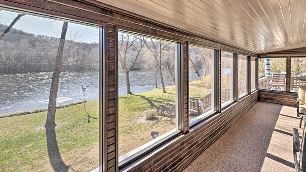 A room with large windows overlooking a river, a wooden ceiling, and a seating area with a view of the outdoors. - White River Fishing Escape w/ Deck & Patio! (Cotter)