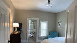 Une chambre à coucher avec un lit, une commode, une chaise, un téléviseur et un ventilateur de plafond.