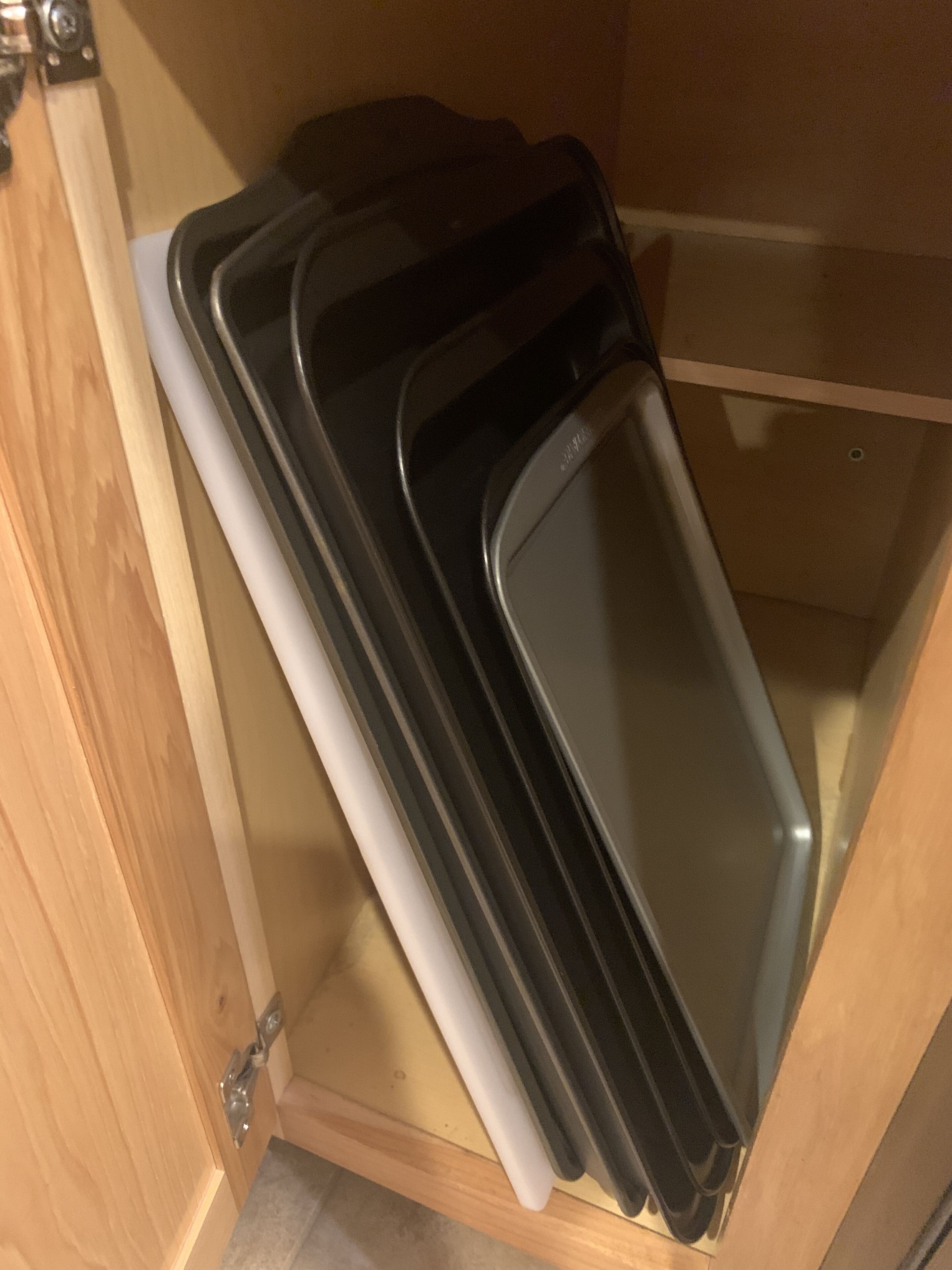 A wooden cabinet with a sliding door containing several black trays.
