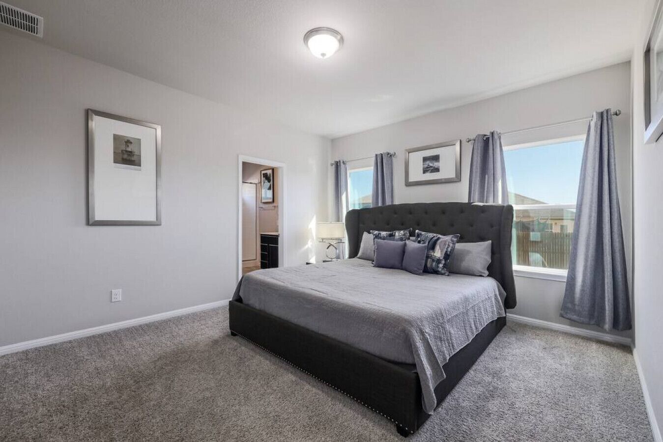 Une chambre à coucher avec un grand lit, un dressing et une fenêtre avec des rideaux.