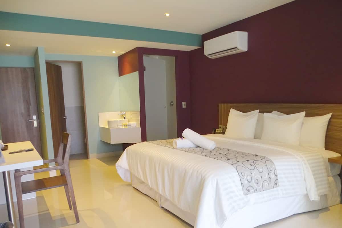 Une chambre d’hôtel équipée d’un lit, d’un bureau, d’une chaise, d’une salle de bain et d’un appareil de climatisation.