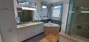 Een bad/douchecombinatie, een bubbelbad, een haardroger, handdoeken