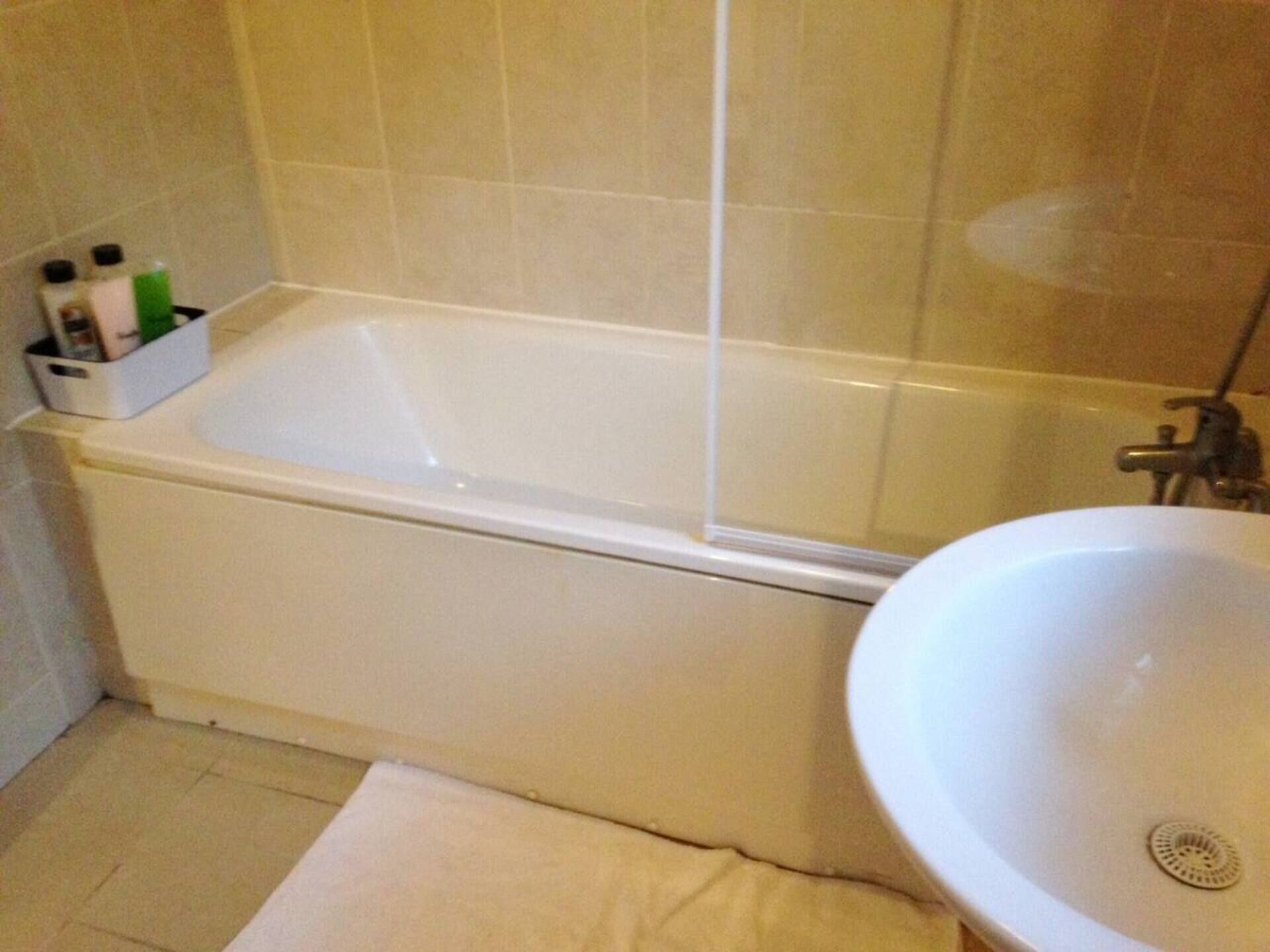 Une salle de bain avec une baignoire, un lavabo et une étagère contenant des articles de toilette.