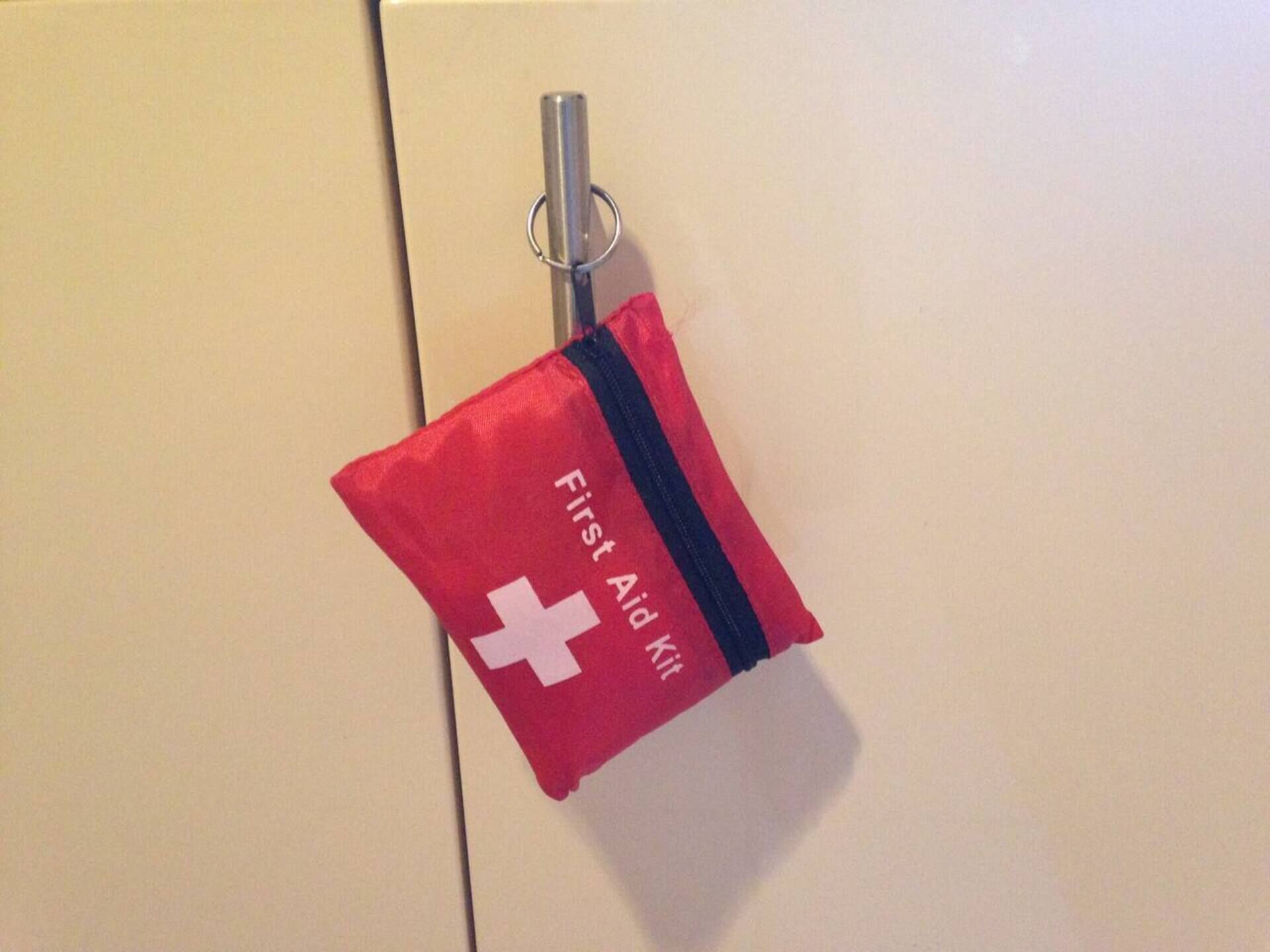 A First Aid kit hanging on a door handle.