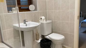 A bathroom with a sink, toilet, and a window with blinds.