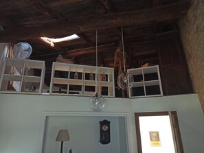 Una habitación rústica con vigas de madera, un reloj y estantes con botellas.
