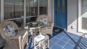 A covered patio area with wicker furniture, a ceiling fan, and a blue door.