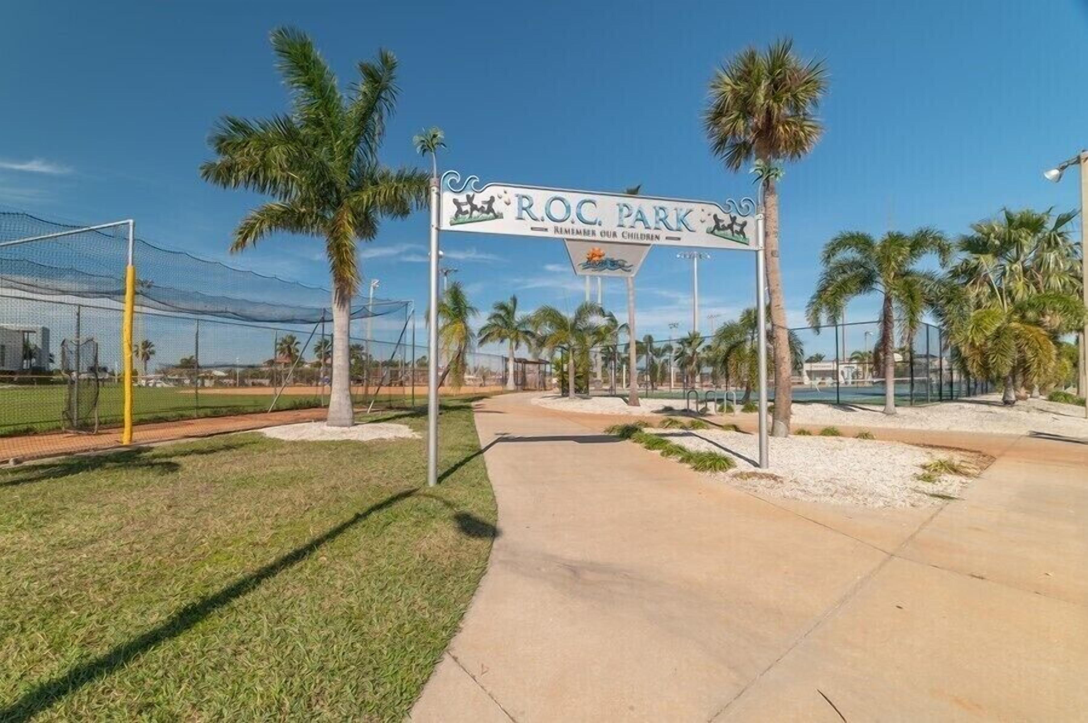 A sports field with a sign reading "R.O.C. Park" and a pathway leading to it.