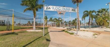 A sports field with a sign reading "R.O.C. Park" and a pathway leading to it.