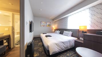 A modern hotel room with a large bed, a desk, a chair, and a TV.
