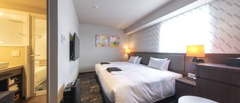 A modern hotel room with a large bed, a desk, a chair, and a TV.