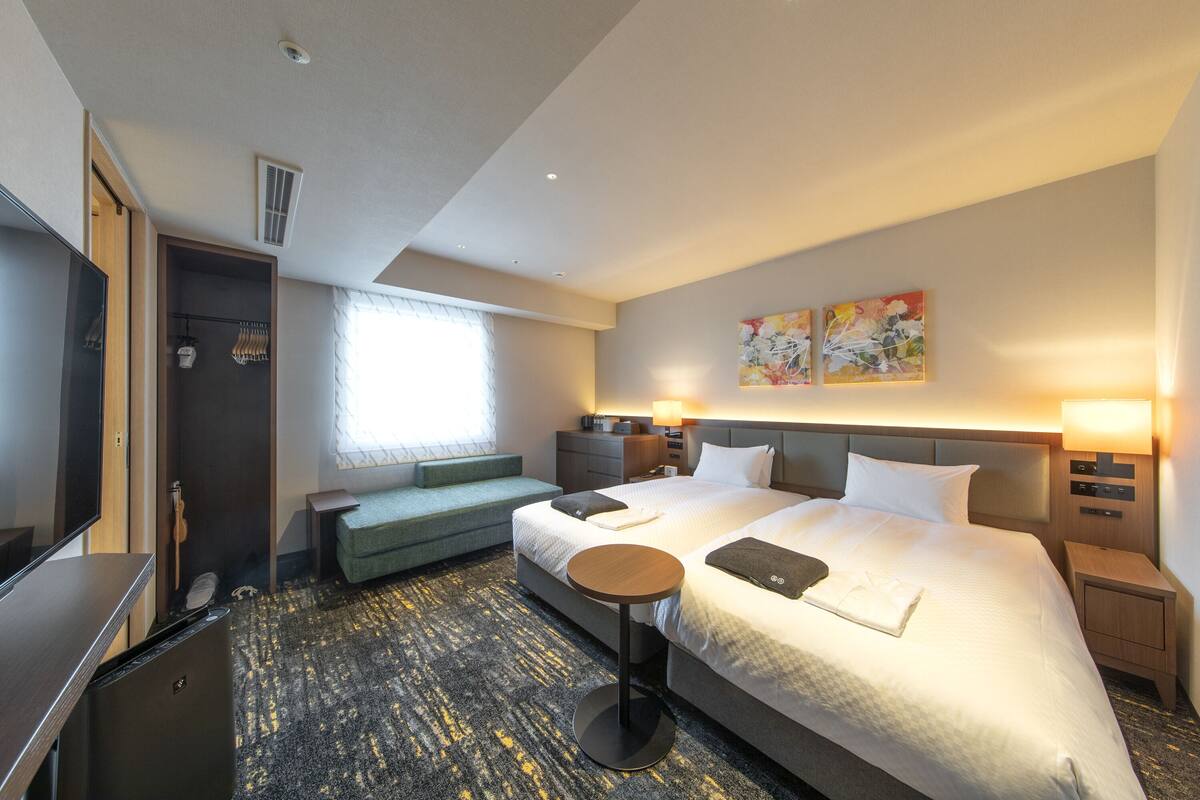 A hotel room with a large bed, a TV, a seating area, and a desk.