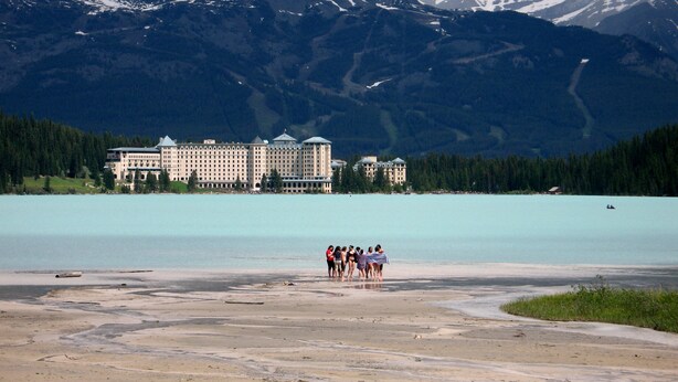 Ein großes Hotel mit mehreren Gebäuden und einem See im Vordergrund.