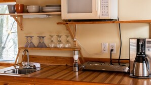 Een keuken met een houten aanrecht, een magnetron, een koffiezetapparaat en een spoelbak.