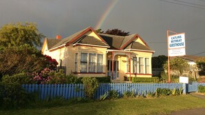 A two-story house with a sign for Catlins Retreat Guesthouse, offering bed & breakfast and en-suite rooms. - Relax in style at the Catlins Retreat, historic villa in the heart of Owaka (Owaka)